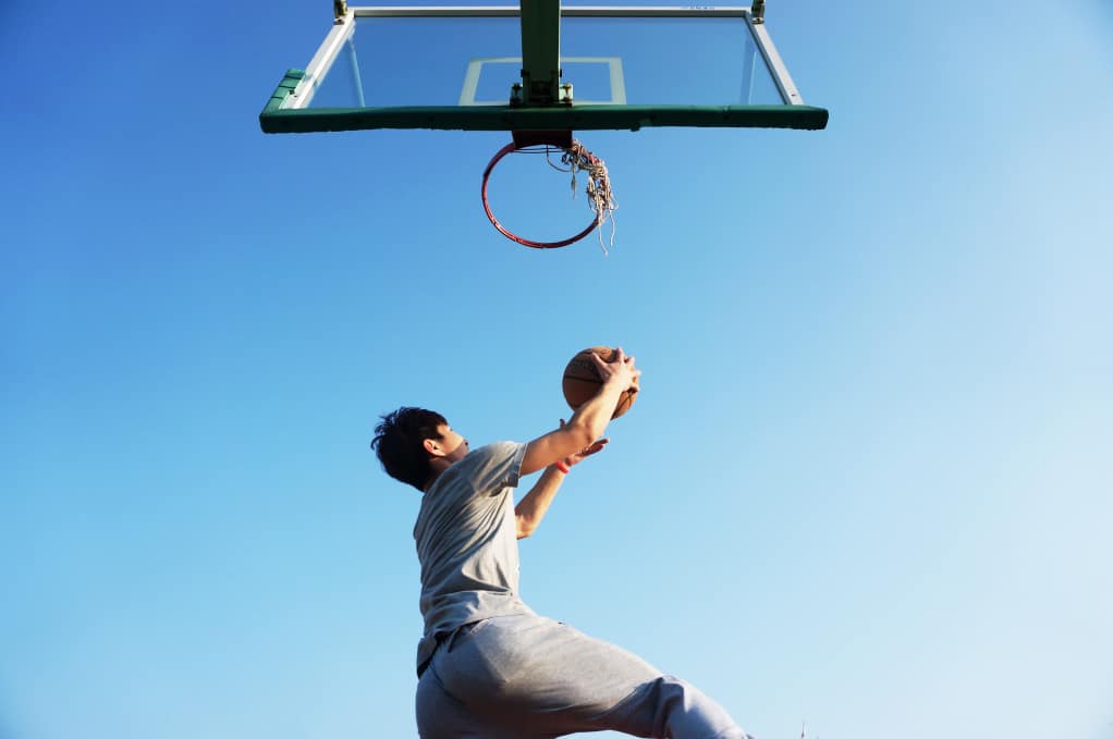 Athlete reaching up to throw a basketball in the hoop