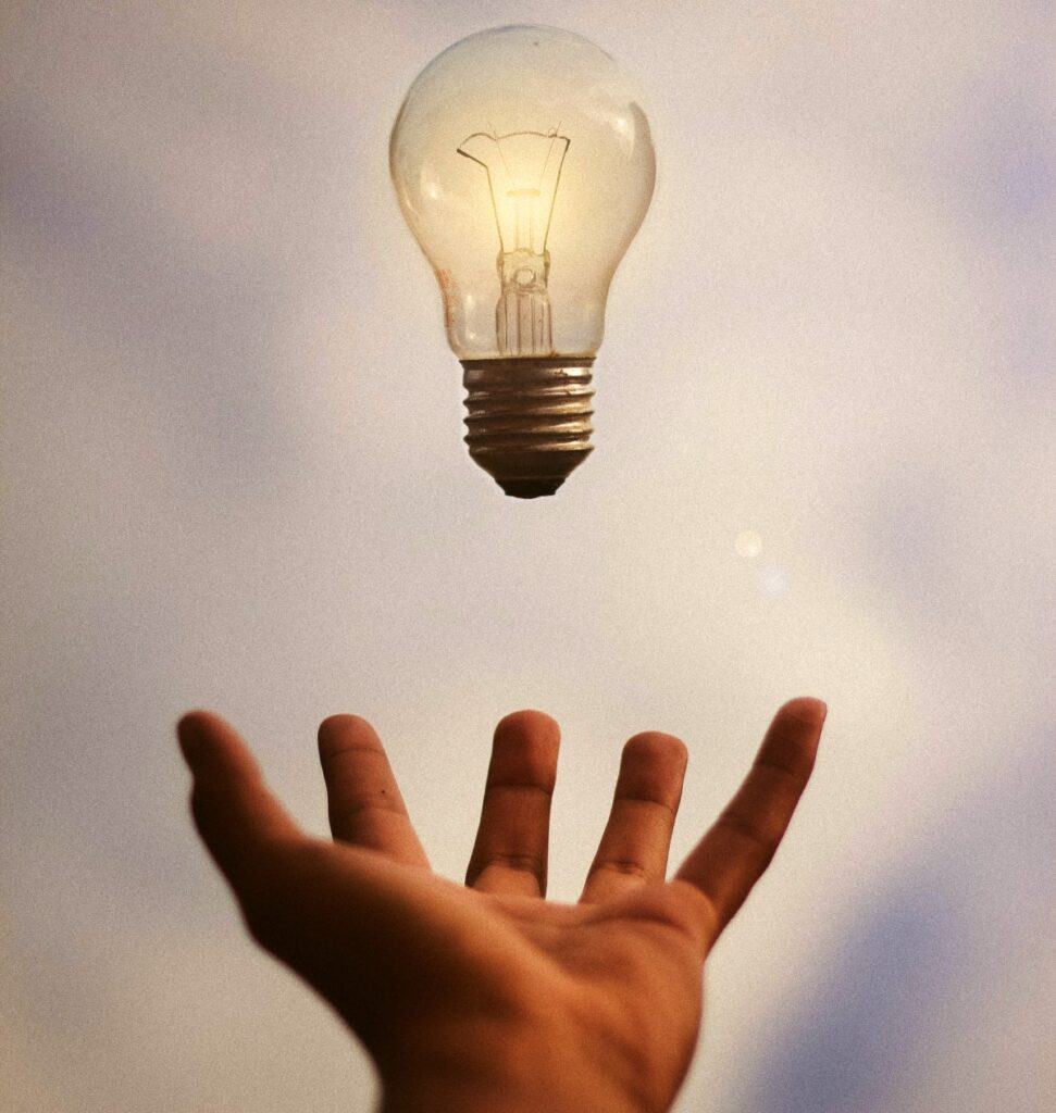Hand With Hovering Lightbulb. Don't Start Marketing Until You're Ready To Learn And Grow